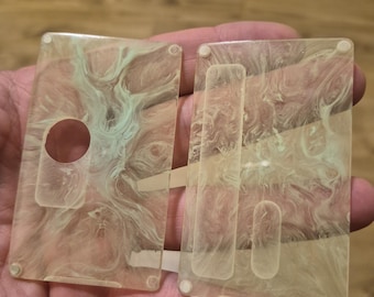 May include: Two rectangular, translucent resin plates featuring a marbled pattern of pale green and cream swirls. The left plate has a circular cutout and a rectangular indentation, while the right plate features two elongated rectangular indentations.