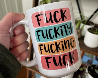 May include: White ceramic coffee mug with a colourful design. The mug has four bands of colour, each with a different word in black lettering. The words are "FUCK", "FUCKITY", "FUCKING", and "FUCK".