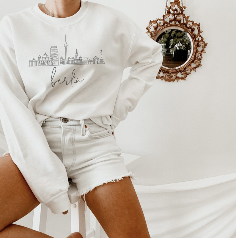 May include: White sweatshirt with a black outline of the Berlin skyline and the word "Berlin" written in cursive below the skyline.