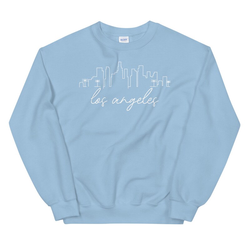 May include: Light blue sweatshirt with a white outline of the Los Angeles skyline and the text "los angeles" in white cursive.
