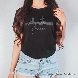 May include: Black t-shirt with a white outline of the Florence skyline and the word "Florence" in cursive.