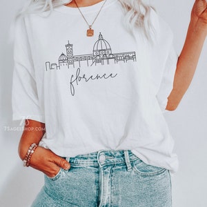May include: White t-shirt with a black line drawing of the Florence skyline, including the Duomo, and the text "florence" underneath.