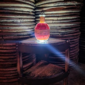 May include: A clear glass bottle with a red liquid inside. The bottle has a label with the words 