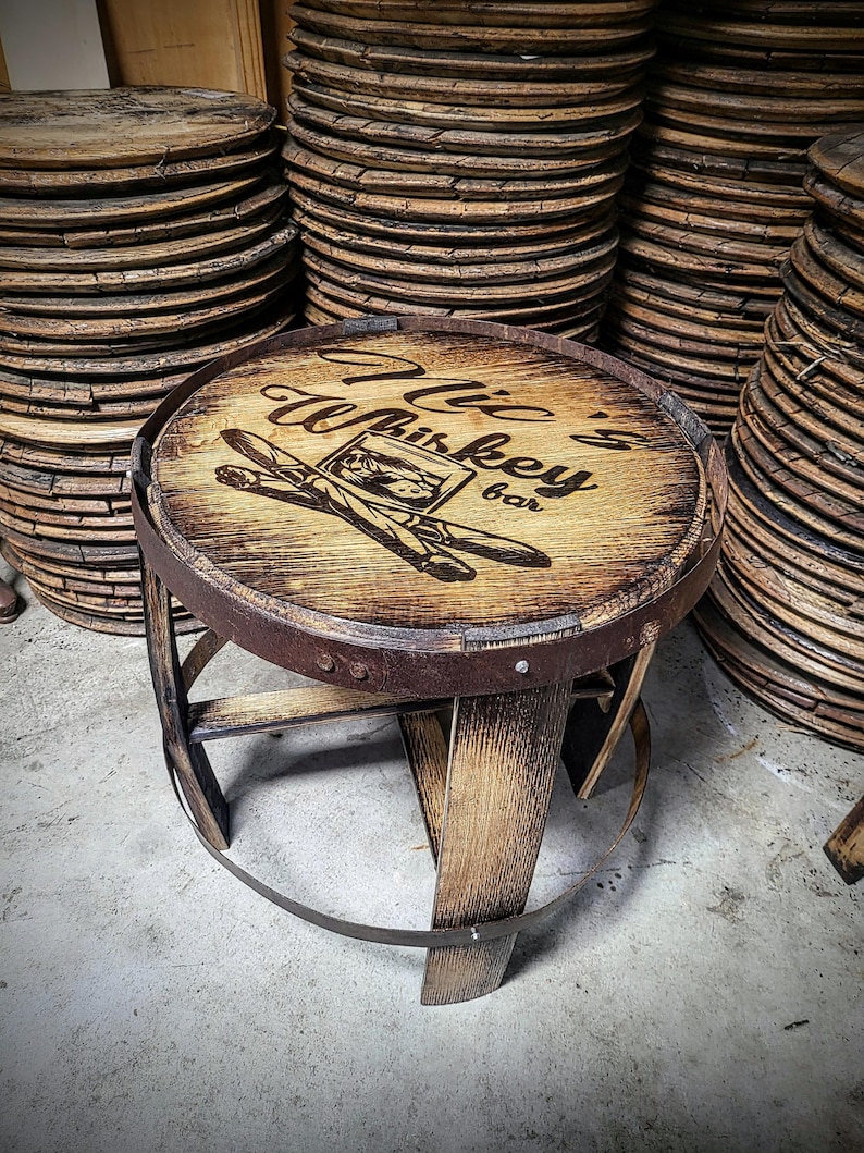 May include: A wooden stool with a round seat made from a repurposed whiskey barrel. The seat has a burnt-in design that says "Willie's Whiskey Bar".