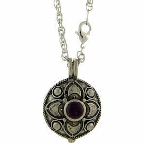 May include: A silver chain necklace with a round pendant featuring a purple gemstone surrounded by an intricate silver design.