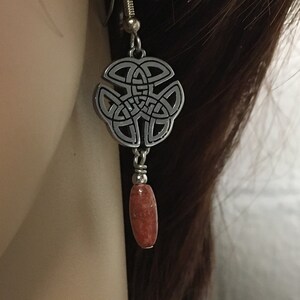 May include: Silver Celtic knot earrings with a dangling orange stone.