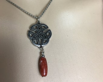 May include: A silver chain necklace with a Celtic knot pendant and a red stone bead.