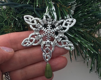 May include: Silver snowflake ornament with a Celtic knot design and a green gemstone pendant.