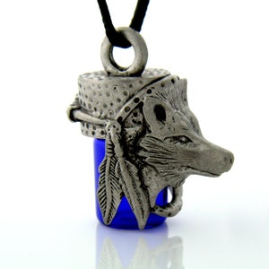 May include: A silver pendant necklace featuring a wolf head design with a blue glass vial. The wolf head is detailed with feathers and a beaded headband.