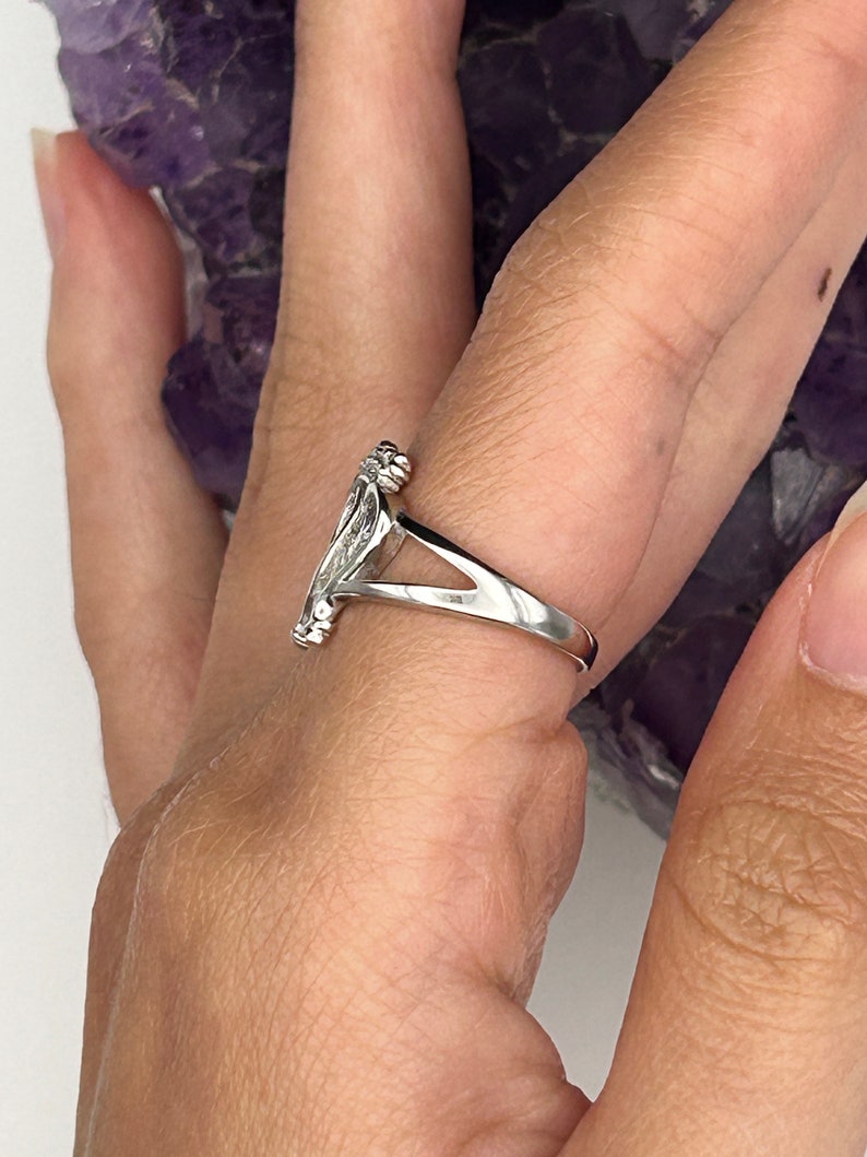 K&ouml;nnte beinhalten: Ein silberner Ring mit einem detaillierten Design, an einem Finger getragen.