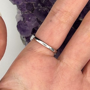 K&ouml;nnte beinhalten: Ein silberner Ring, der an einem Finger getragen wird. Der Ring ist schlicht und hat eine glatte, polierte Oberfl&auml;che.