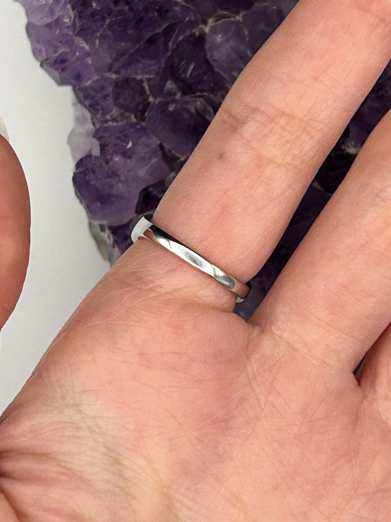K&ouml;nnte beinhalten: Ein silberner Ring, der an einem Finger getragen wird. Der Ring ist schlicht und hat eine glatte, polierte Oberfl&auml;che.