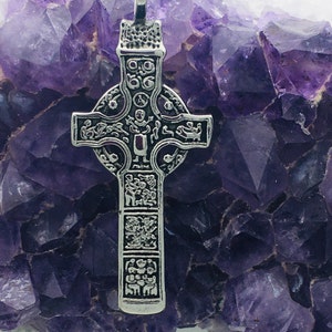 May include: A silver Celtic cross pendant with intricate knotwork and detailed figures, set against a backdrop of purple amethyst crystals.