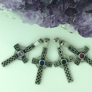 May include: Four silver Celtic cross pendants with different colored gemstones in the center. The crosses are intricately detailed with a knotwork design. The gemstones are amethyst, sapphire, emerald, and ruby.