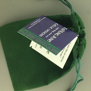 May include: A green velvet drawstring bag with a blue and white card inside. The card has the text "Ashing Aine (ash+ling, awn+ye) Celtic Designs" and a quote: "the most that you wish for that you get."