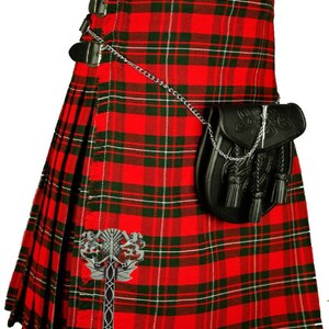 May include: A red, green, and white plaid kilt with a black leather sporran and a silver chain. The kilt has a silver kilt pin with a Celtic knot design.