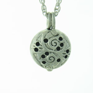 May include: Silver pendant necklace with a round, ornate charm featuring a floral design with cut-out details.