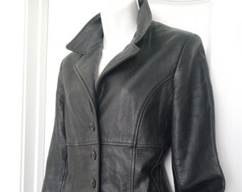 Könnte beinhalten: Schwarze Lederjacke mit Reverskragen und drei Knöpfen. Die Jacke hat eine taillierte Passform mit Nähten und einem Taschen Detail. Die Jacke wird auf einer weißen Schaufensterpuppe vor weißem Hintergrund präsentiert.