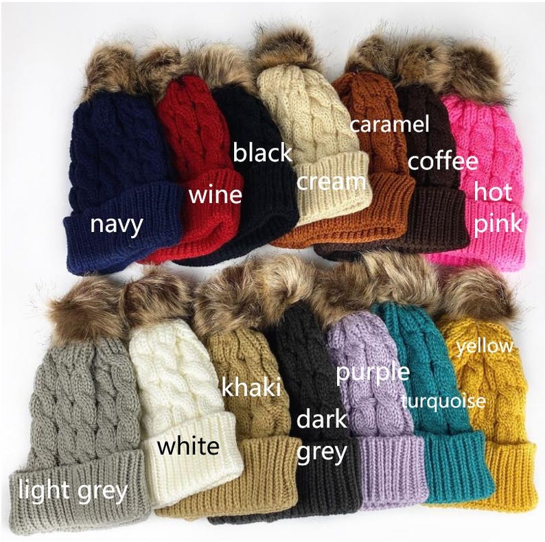 May include: Assortment of 12 knitted winter hats with faux fur pom poms in various colors, including navy, wine, black, cream, caramel, coffee, hot pink, yellow, turquoise, khaki, purple, dark grey, light grey and white.