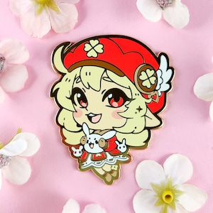 May include: Gold enamel pin featuring a cartoon character with blonde hair, wearing a red hat with a clover design and holding a small white animal. The character has a happy expression and is wearing a white dress with a green clover design.