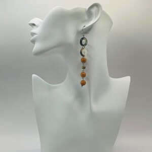May include: Long dangle earrings with brown and white beads and a silver ring.