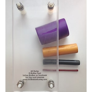 May include: A clear acrylic EZ Roller tool with various components. Includes a purple cup, wooden dowel, and black and red rods. Text on the tool reads "EZ Roller A Bcr8ve Tool" and provides social media and website information.