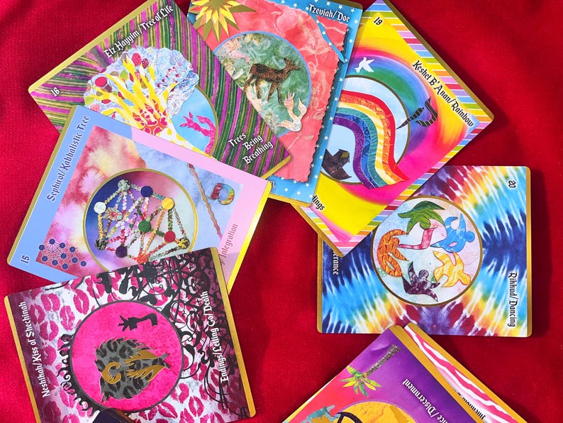 May include: A collection of colorful tarot cards with various illustrations and text. The cards feature images of trees, rainbows, and abstract designs. The text includes phrases like "Tree of Life" and "Rainbow".