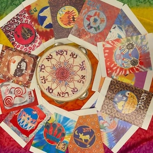 May include: A tambourine surrounded by colorful, tie-dye style cards with various circular designs. The tambourine has text in a circular pattern around a central floral design. The cards feature images of hands, animals, and other symbols.