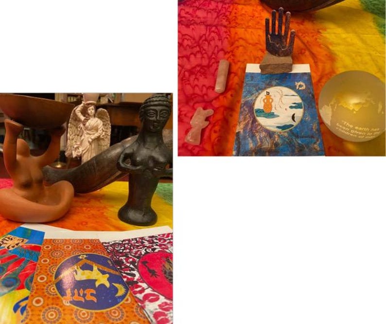 May include: A collection of spiritual and decorative items, including statues, a wooden hand sculpture, crystals, and a glass globe. The items are arranged on a colorful, patterned fabric, creating a vibrant and eclectic display.