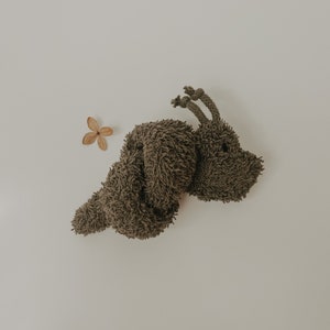 May include: A brown plush toy shaped like a curled-up animal with two long ears. The toy is on a white background.