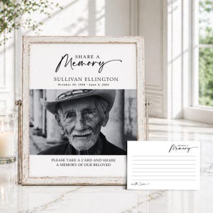 May include: A framed memorial sign with a black and white photo of an older man wearing a hat. The sign reads "Share a Memory" and includes the name Sullivan Ellington and dates. A small card with lines and "Share a Memory" is also present.