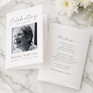 May include: A white memorial card featuring a black and white photograph of a smiling woman. The card is inscribed with "Celebrating the Life of Melanie Anderson" and dates. The inside reads "thank you" and a message of gratitude from The Anderson Family.