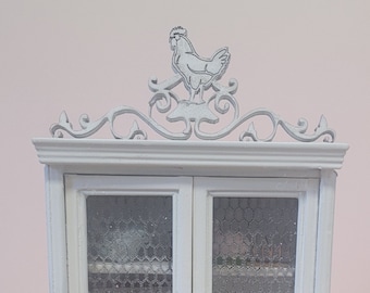 May include: White wooden cabinet with glass doors and a single drawer. The cabinet has a decorative rooster design on top and a wire mesh behind the glass doors.