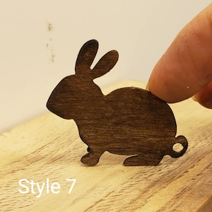 May include: A dark brown wooden rabbit cutout with a smooth, polished finish. The rabbit is in a sitting position with its ears upright. The cutout is on a light brown wooden surface. The text "Style 7" is visible in the lower left corner of the image.