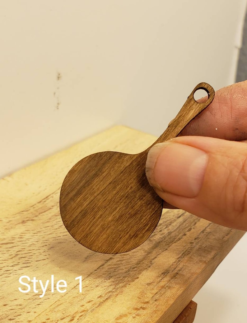 May include: A small, round, wooden cutting board with a handle. The board is stained a dark brown color. The board is labeled "Style 1".