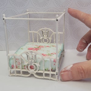 Puede incluir: Cama de metal blanco para casa de mu&ntilde;ecas con dosel y colcha con estampado floral.