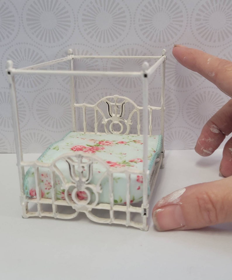 Puede incluir: Cama de metal blanco para casa de mu&ntilde;ecas con dosel y colcha con estampado floral.