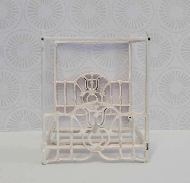 Puede incluir: Estructura de cama con dosel de metal blanco con detalles intrincados. El marco est&aacute; hecho de metal delgado y tiene un dise&ntilde;o delicado y ornamentado.