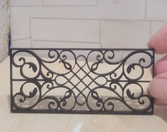 May include: Black metal decorative railing with a scroll design. The railing is made of thin metal and has a delicate, intricate pattern.