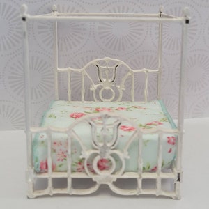 Puede incluir: Cama de metal blanco para casa de mu&ntilde;ecas con dosel y colch&oacute;n con estampado floral.