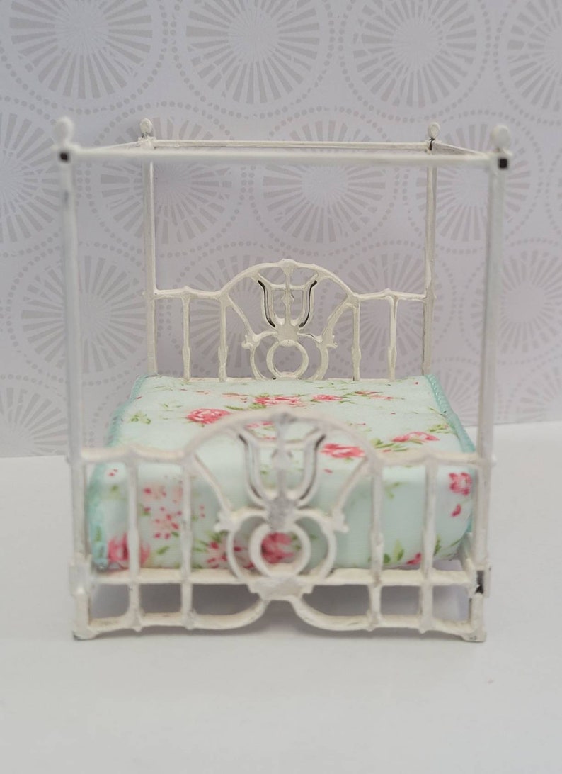 Puede incluir: Cama de metal blanco para casa de mu&ntilde;ecas con dosel y colch&oacute;n con estampado floral.