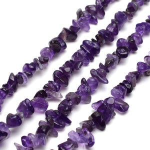 Op de afbeelding: Een streng amethyst edelsteen chips, met meerdere strengen van de chips in een rij gelegd. De chips zijn diep paars van kleur en hebben een natuurlijke, onregelmatige vorm.