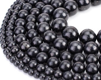 May include: A strand of black obsidian beads, with varying sizes, arranged in a circular pattern. The beads have a smooth, polished finish.