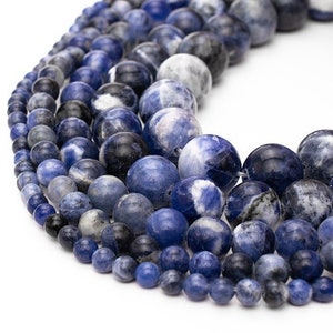 May include: A strand of blue and white gemstone beads. The beads are round and have a smooth, polished finish. The beads are arranged in a graduated size, with the largest beads at the top and the smallest beads at the bottom.
