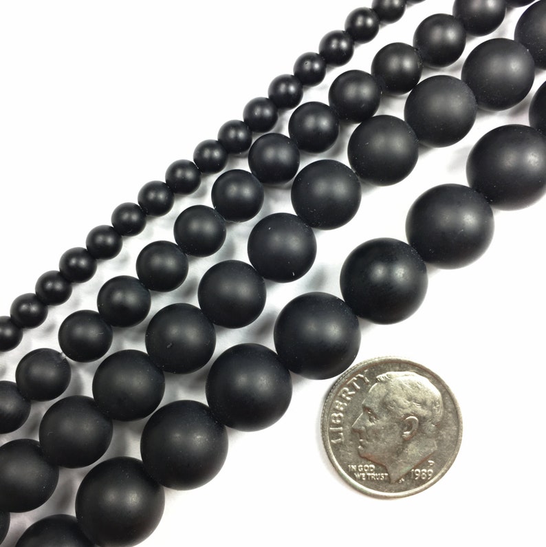 May include: Four strands of black matte round beads of varying sizes. The beads are arranged in a line, with the largest beads at the bottom and the smallest beads at the top. A US dime is included for scale.