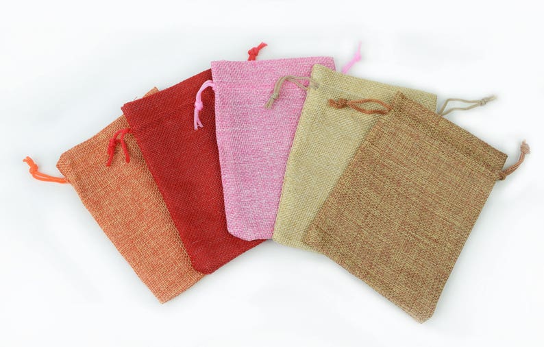 May include: Five small drawstring bags made of burlap fabric in various colors, including orange, red, pink, beige, and brown.