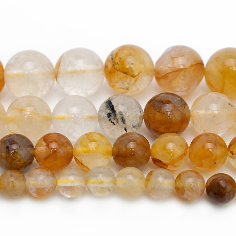 May include: A strand of round, translucent beads with shades of clear, yellow, and brown. The beads have a natural, organic look with inclusions of gold and brown.