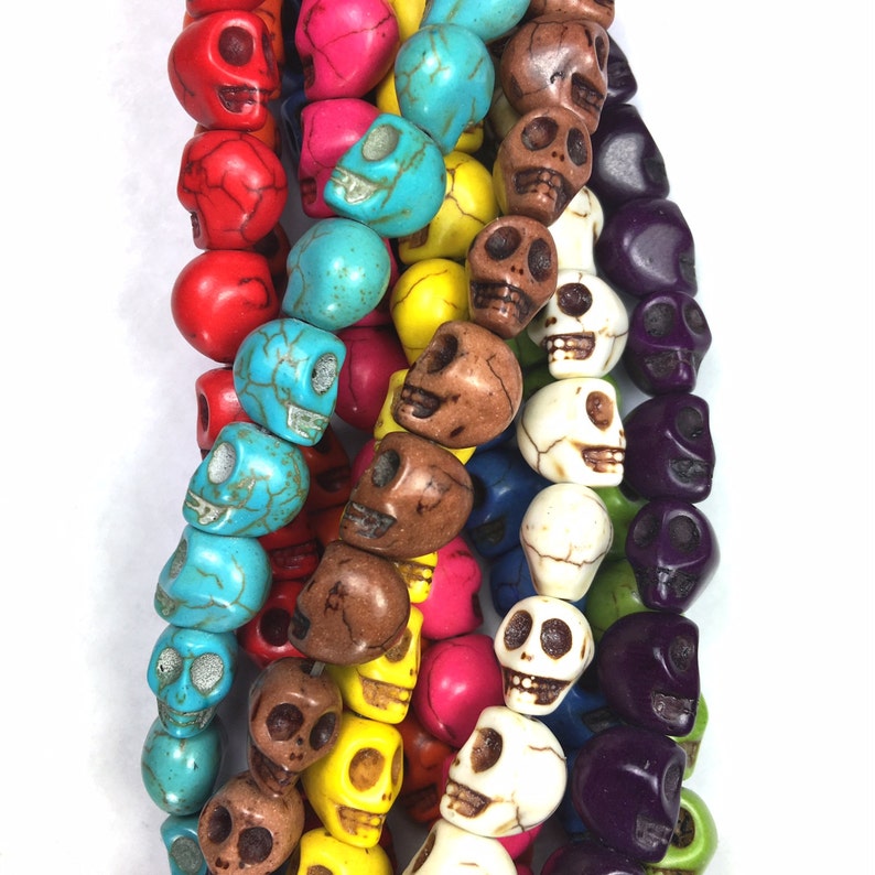Puede incluir: Una hebra de cuentas de calavera de colores, con cuentas turquesa, rojas, blancas, marrones, amarillas y moradas. Las cuentas est&aacute;n hechas de hueso y tienen un dise&ntilde;o de calavera tallado.