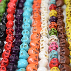 Puede incluir: Primer plano de una variedad de cuentas de calavera de colores. Las cuentas est&aacute;n hechas de turquesa, rojo, naranja, blanco, amarillo, marr&oacute;n, verde, negro y azul.