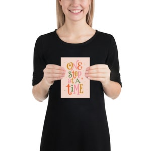 May include: A pink card with the text "ONE step at a time" in colorful, stylized lettering.
